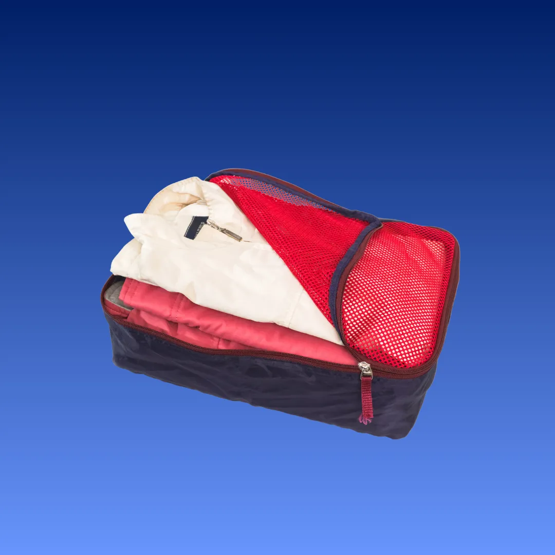 Packing cube berisi pakaian, dengan panel jaring dan ritsleting keliling.