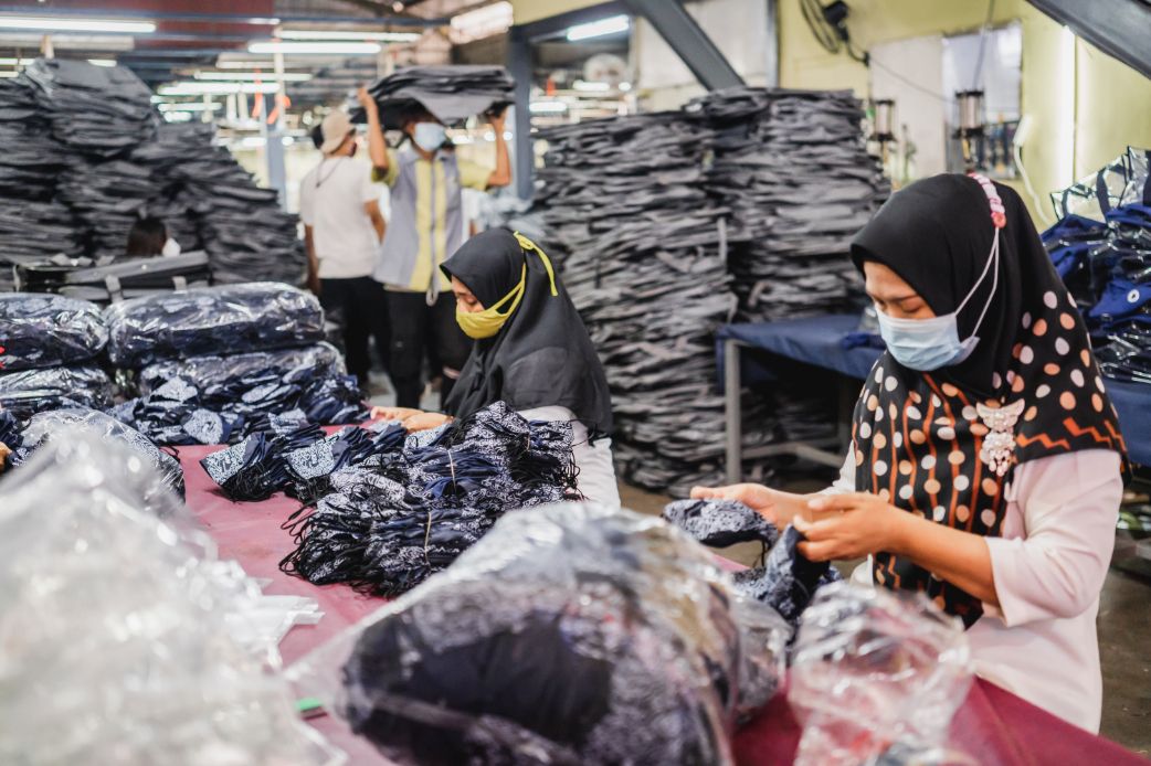 Pekerja mengemas tas jadi ke dalam kantong plastik satuan sebelum masuk karton.